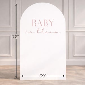 May include: A white, arched backdrop with the text "BABY in bloom" in pink. The backdrop is 183 cm tall and 99 cm wide. Suitable for baby showers or gender reveal events.