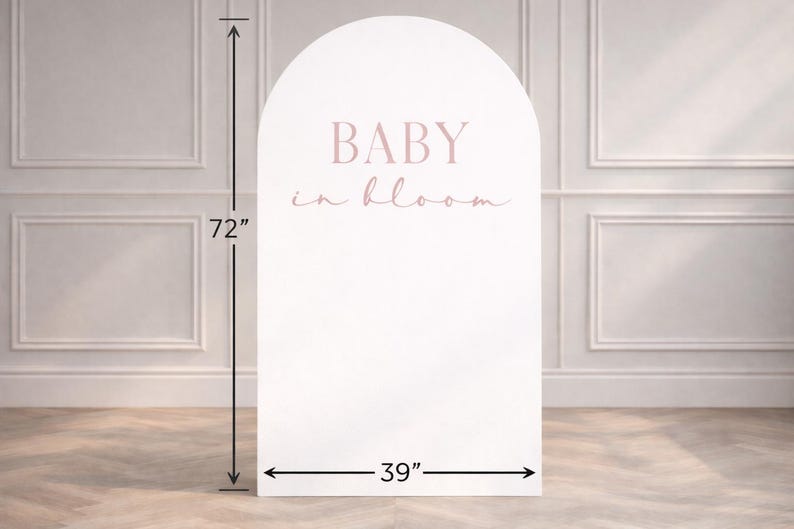 May include: A white, arched backdrop with the text "BABY in bloom" in pink. The backdrop is 183 cm tall and 99 cm wide. Suitable for baby showers or gender reveal events.