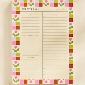 May include: A floral-themed daily planner with the text "TODAY'S PLAN." The planner features sections for priorities, hourly scheduling, notes, and tomorrow. The border has a repeating pattern of pink flowers and colorful squares.