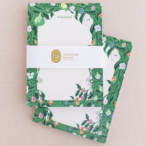 May include: A notepad with a green floral design featuring pears, flowers, and leaves. The notepad has 50 sheets and says "Flourish" on the front.