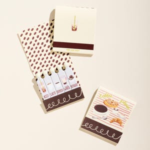 May include: A collection of coffee-themed notepads. One notepad features a drink in a clear cup, while another displays coffee beans. The third notepad has the words "Coffee Please" and images of coffee and pastries.