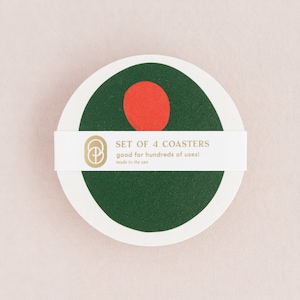 May include: Set of 4 green and red coasters with a white border. The coasters have a simple geometric design. The text on the label reads "SET OF 4 COASTERS good for hundreds of uses! made in the USA".