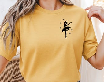 Könnte beinhalten: Ein senfgelbes T-Shirt mit kurzen Ärmeln und einer schwarzen Grafik im linken Brustbereich. Die Grafik zeigt die Silhouette einer Ballerina in einer Tanzpose, umgeben von mehreren kleinen, einfachen sternförmigen Symbolen.
