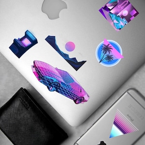 Puede incluir: Una colección de pegatinas coloridas de estilo retro en un portátil y un teléfono. Las pegatinas presentan un coche, palmeras y formas geométricas en vibrantes tonos rosas, azules y morados. También se ve una cartera negra.