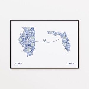 May include: A framed print showing the outlines of Illinois and Florida, linked by a heart-shaped line. The states are filled with a blue and white floral design. The word "Illinois" is written below the Illinois outline, and "Florida" below the Florida outline.