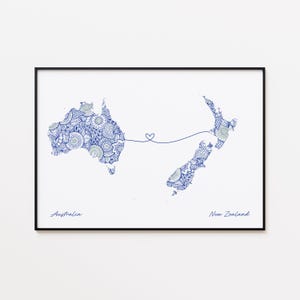 May include: A framed print showing stylized maps of Australia and New Zealand, linked by a heart-shaped line. The maps are filled with detailed blue and white patterns. The word "Australia" is written below the map of Australia, and "New Zealand" below the map of New Zealand.