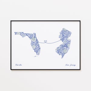 May include: A framed print featuring detailed blue and white patterned maps of Florida and New Jersey, connected by a heart-shaped line. The words "Florida" and "New Jersey" are written below the respective states.