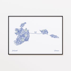 May include: A framed print featuring blue patterned maps of Ireland and Samoa, connected by a heart-shaped line. The names "Ireland" and "Samoa" are written below the maps in a handwritten font. The print is set against a white background.