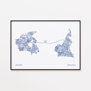 May include: A framed print featuring detailed blue and white patterned maps of Canada and Cameroon, connected by a line with a heart. The words "Canada" and "Cameroon" are written below the maps in a handwritten font.