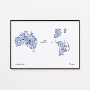 May include: A framed print showing detailed blue and white patterned maps of Australia and Macau, linked by a heart-shaped line. The word "Australia" is written below the map of Australia, and "Macau" is written below the map of Macau.