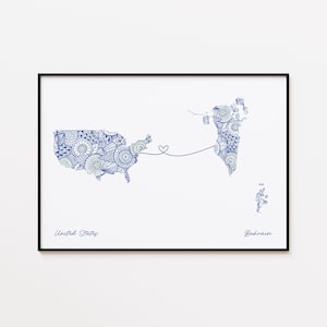 May include: A framed print featuring a blue and white patterned map of the United States and Bahrain, connected by a heart-shaped line. The words "United States" and "Bahrain" are written in a handwritten font below the maps.