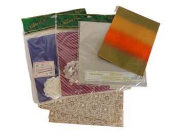 May include: Assortment of gift wrap sheets in various designs. Includes a blue sheet with a "Celebration" sticker, a red and white striped sheet with a bow, and a sheet with an orange, yellow, and green gradient. Also includes a sheet with a beige floral pattern.