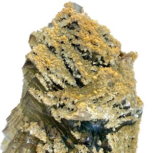 May include: A close-up of a natural mineral specimen. The mineral features layered, translucent green and purple sections with a crystalline structure. The surface is coated with a layer of tan and white granular material, creating a textured appearance.