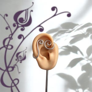 Pode incluir: Um brinco de orelha prateado com um design em espiral é exibido em uma orelha de manequim. O brinco de orelha envolve a orelha e apresenta dois detalhes em espiral. O fundo inclui um design floral roxo e sombras.