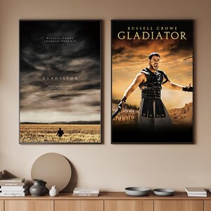 Könnte beinhalten: Zwei gerahmte Filmplakate. Das linke Poster zeigt einen dramatischen Himmel über einem Feld mit dem Wort "Gladiator". Das rechte Poster zeigt Russell Crowe in "Gladiator" mit dem Filmtitel darüber.