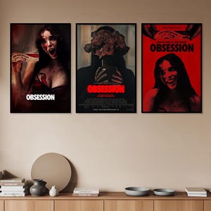 Puede incluir: Tres carteles de cine rectangulares titulados Obsession en marcos negros. Los carteles de la izquierda y la derecha muestran a una persona con sangre en la cara sosteniendo una caja de One Wish Willow. El cartel central muestra un jarrón con rosas.
