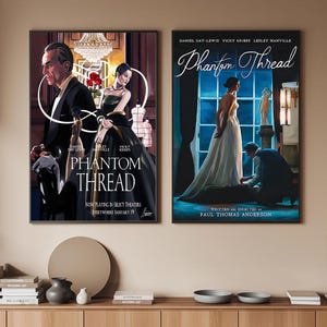 May include: Two framed movie posters for "Phantom Thread" are displayed. The posters feature Daniel Day-Lewis, Vicky Krieps, and Lesley Manville. One poster shows a man and woman in formal attire, the other a woman in a white gown.