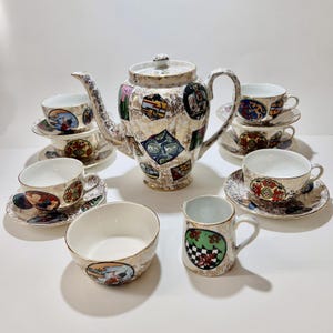 May include: A complete vintage tea set, including a teapot, cups, saucers, a creamer jug, and a sugar bowl. The set is decorated in gold and cream, with colourful patterned details. The teapot, with its curved spout and handle, is the focal point.