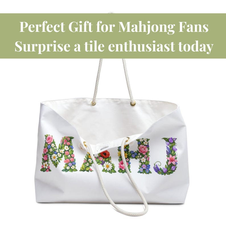 May include: White tote bag with the word "MAHJ" spelled out in colorful floral letters. The bag has rope handles and gold-colored eyelets. Text at the top reads "Perfect Gift for Mahjong Fans Surprise a tile enthusiast today."