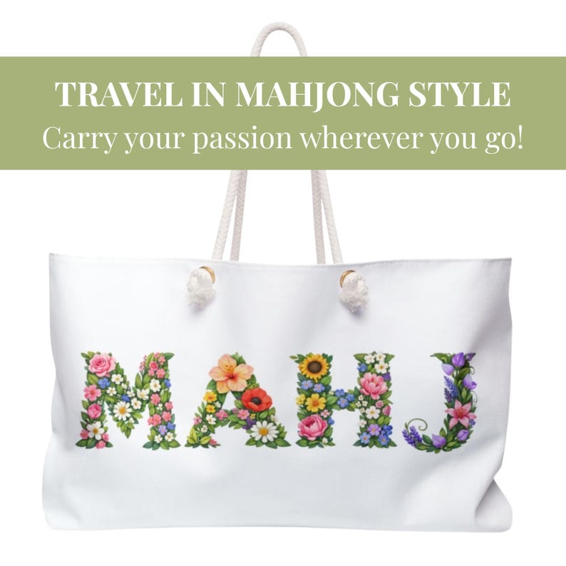 May include: White tote bag with rope handles. The word "MAHJ" is spelled out in colorful floral letters. The text "TRAVEL IN MAHJONG STYLE" and "Carry your passion wherever you go!" are printed above the bag.
