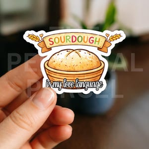 May include: A sticker featuring a cartoon illustration of a sourdough loaf in a basket. The banner above reads "SOURDOUGH" in colorful letters, and below it, the text "is my love language" is written in a script font.
