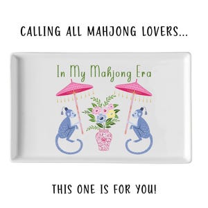 May include: White rectangular tray with the text "CALLING ALL MAHJONG LOVERS... In My Mahjong Era THIS ONE IS FOR YOU!". The tray features a design with two blue monkeys holding pink parasols, and a vase of flowers.