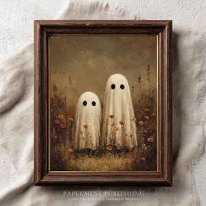 May include: A framed vintage-inspired print featuring two white ghost figures with black eyes in a field of wildflowers. The artwork has a dark brown wooden frame and the text "PAPERMUSE PUBLISHING" at the bottom.