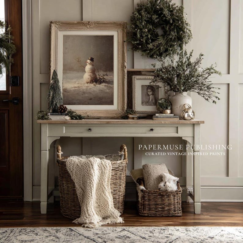 May include: A vintage-inspired interior scene featuring a console table adorned with framed artwork, a wreath, and decorative items. Woven baskets hold a blanket and pillows. The scene evokes a cozy, rustic aesthetic, perfect for home decor.