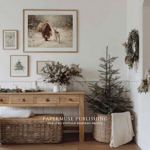 Puede incluir: Una escena interior acogedora con una consola de madera, una cesta de mimbre y un peque&ntilde;o &aacute;rbol de Navidad en una cesta. Obras de arte enmarcadas en la pared representan a Pap&aacute; Noel y un ciervo. Una corona y otras decoraciones crean un ambiente festivo.