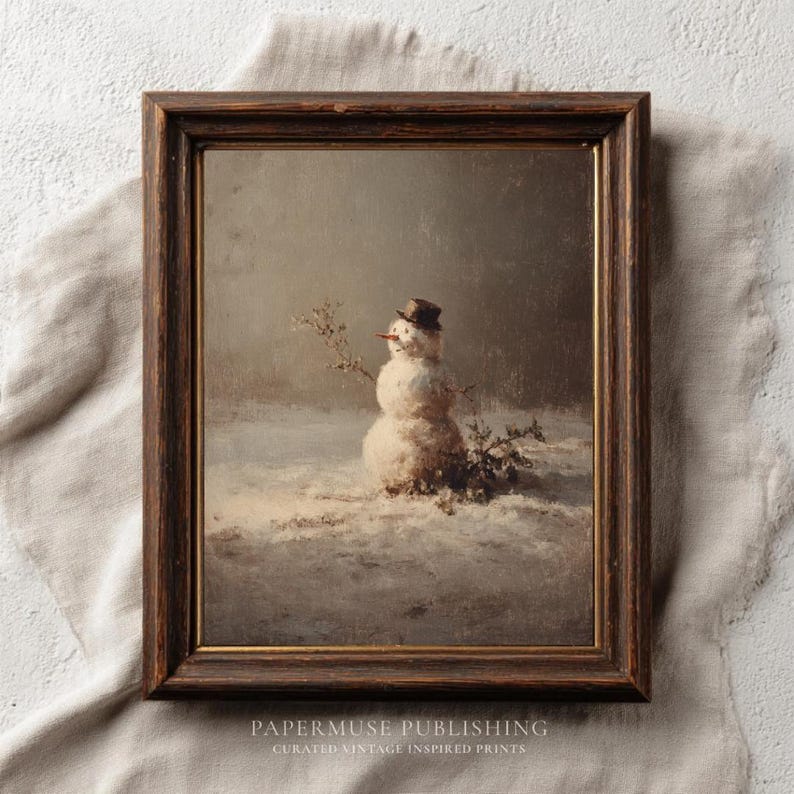 May include: Framed vintage print of a snowman in a snowy landscape. The snowman wears a small top hat and has a carrot nose. The artwork is in a dark wooden frame and features the text "PAPERMUSE PUBLISHING" at the bottom.