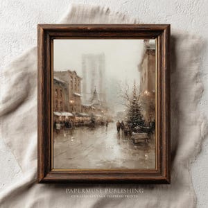 May include: A framed vintage print showing a snowy street scene with buildings, streetlights, and a Christmas tree. The artwork uses a muted palette of browns, greys, and whites, creating a nostalgic feel. The frame is dark brown.