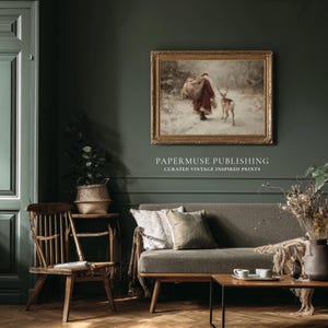 Puede incluir: Una impresi&oacute;n vintage enmarcada que representa una figura con abrigo rojo y un ciervo en un paisaje nevado. La impresi&oacute;n cuelga sobre un sof&aacute; gris con cojines decorativos. El texto "PAPERMUSE PUBLISHING CURATED VINTAGE INSPIRED PRINTS" est&aacute; debajo.