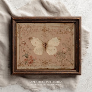 May include: A framed vintage print featuring a detailed illustration of a white butterfly with brown markings, centered on a pink background with floral and ornamental details. The dark brown frame surrounds the artwork. Text at the bottom reads "PAPERMUSE PUBLISHING".