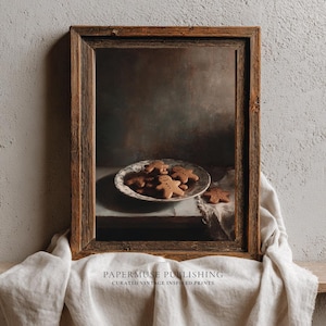 Puede incluir: Impresión enmarcada con hombres de jengibre en un plato decorativo. El marco de madera rústica rodea la imagen. El texto "PAPERMUSE PUBLISHING" y "CURATED VINTAGE INSPIRED PRINTS" es visible. Un paño de lino está debajo.