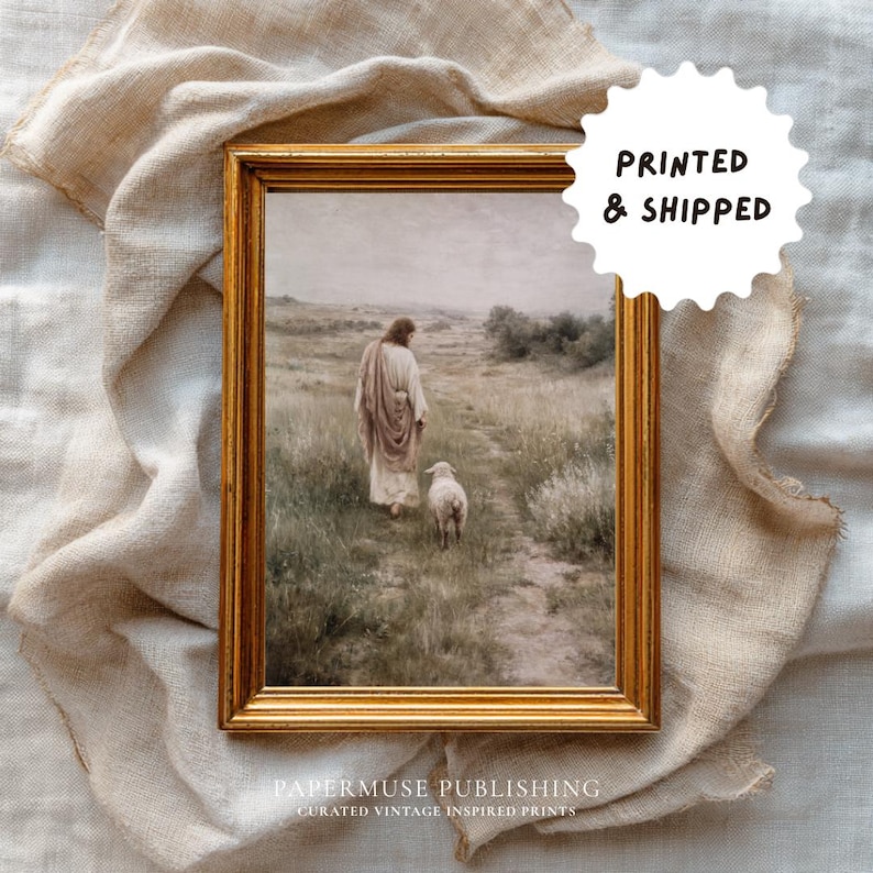 May include: A framed print with a gold-colored frame. The artwork depicts a person in a robe walking with a lamb on a path through a field. The text "PRINTED & SHIPPED" is in a white circle. The text "PAPERMUSE PUBLISHING" is at the bottom.
