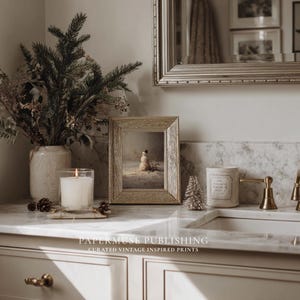May include: A framed vintage print of a snowman in a snowy landscape sits on a marble countertop, next to a lit candle, a small silver Christmas tree, and a decorative jar. The text "PAPERMUSE PUBLISHING" and "CURATED VINTAGE INSPIRED PRINTS" are visible.