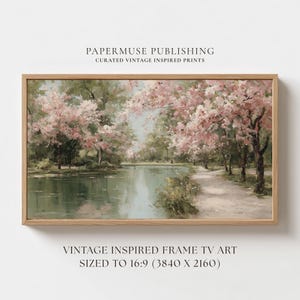Pode incluir: Uma impressão emoldurada de uma paisagem com uma cena serena à beira-mar com um caminho e árvores em flor. A obra de arte tem uma estética vintage, com cores suaves e uma moldura de madeira natural. O texto na impressão diz "PAPERMUSE PUBLISHING" e "VINTAGE INSPIRED FRAME TV ART".