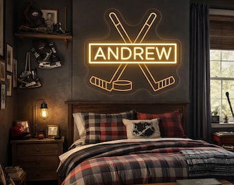 Könnte beinhalten: Schlafzimmer mit Hockey-Thema. Ein Neonschild mit dem Namen "ANDREW" befindet sich über dem Bett, mit gekreuzten Hockeyschlägern und einem Puck. Das Bett hat eine karierte Bettdecke und Kissen. Hockeyausrüstung schmückt die Wände.
