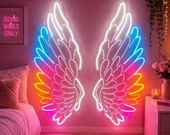 May include: A large neon wall sign featuring two symmetrical angel wings. The wings are outlined in bright white, yellow, orange, pink, and blue neon tubing, creating a vibrant gradient effect against the wall. The design is mounted on a wall.
