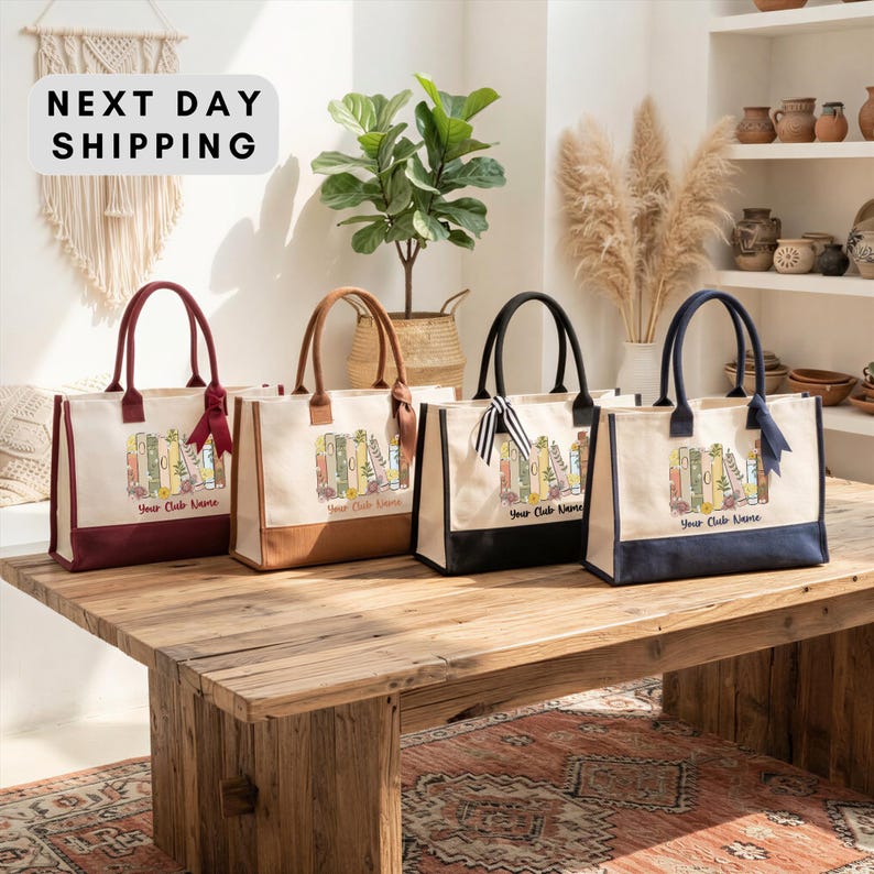 four tote bags with printed designs, arranged on a wooden table. The bags are of different colors and sizes, and they appear to be made of canvas or leather. The background features a beige wall with a hanging plant and shelves displaying various decorative items.