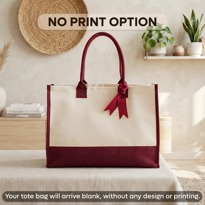 A large tote bag with a maroon trim and a white interior, placed on a wooden surface against a beige wall with a woven basket.
