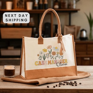 May include: A canvas tote bag with a floral design and the text "CASE MANAGER Olivia." The bag has brown handles and trim, and is sitting on a burlap cloth. A small glass of coffee sits to the left.