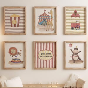 May include: A nursery wall decor arrangement featuring six framed circus-themed prints. The prints depict popcorn, a circus tent with a giraffe, a popcorn cart, a lion on a circus drum, a sign that reads 'Where Dreams Take Center Stage', and a monkey with a balloon. The color palette includes beige, red, and brown.
