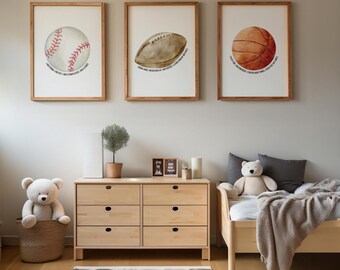 May include: Three framed prints featuring watercolour illustrations of a baseball, a rugby ball, and a basketball. Each print has a quote. The prints are in wooden frames, displayed above a wooden chest of drawers and a bed.
