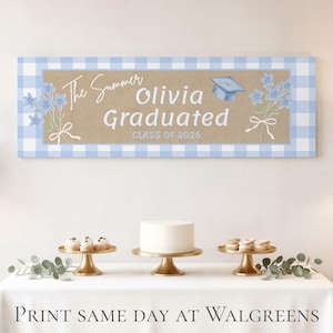 Peut inclure: Une bannière de remise de diplôme avec une bordure vichy bleue et un centre en papier kraft. La bannière indique "The Summer Olivia Graduated CLASS OF 2026" avec des illustrations florales et un mortier. Une table présente un gâteau et des pâtisseries.
