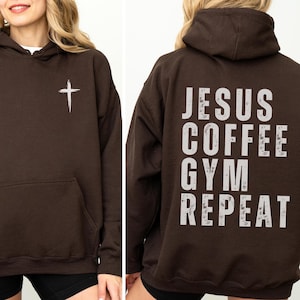 May include: A brown hooded sweatshirt with a white cross on the front and the words "JESUS COFFEE GYM REPEAT" printed on the back. The sweatshirt has a front pocket and a hood.