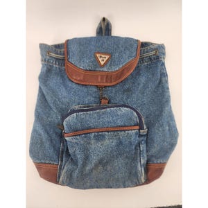 Peut inclure: Sac à dos en jean bleu avec des détails en cuir marron. Il possède une poche avant zippée et une fermeture à rabat. Le rabat porte un logo Route 66. Le sac a une fermeture à cordon et une poignée supérieure.