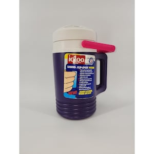 May include: A purple Igloo Legend Flip-Spout pitcher with a white lid and a pink handle. The pitcher has a black handle and a label with the text "NEW! HANDY AT HOME WORK OR PLAY!"