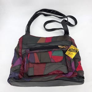 Puede incluir: Un bolso de hombro de patchwork multicolor hecho de piezas de cuero genuino en tonos negro, burdeos, morado y verde. El bolso cuenta con una cremallera superior, un bolsillo frontal con solapa y una etiqueta amarilla con el texto Tinder Genuine Leather.