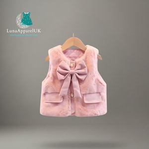 May include: A pink faux fur vest with a large bow detail and two small pockets. The vest has a quilted lining and is fastened with three gold buttons. The Luna Apparel UK logo is visible in the top left corner.